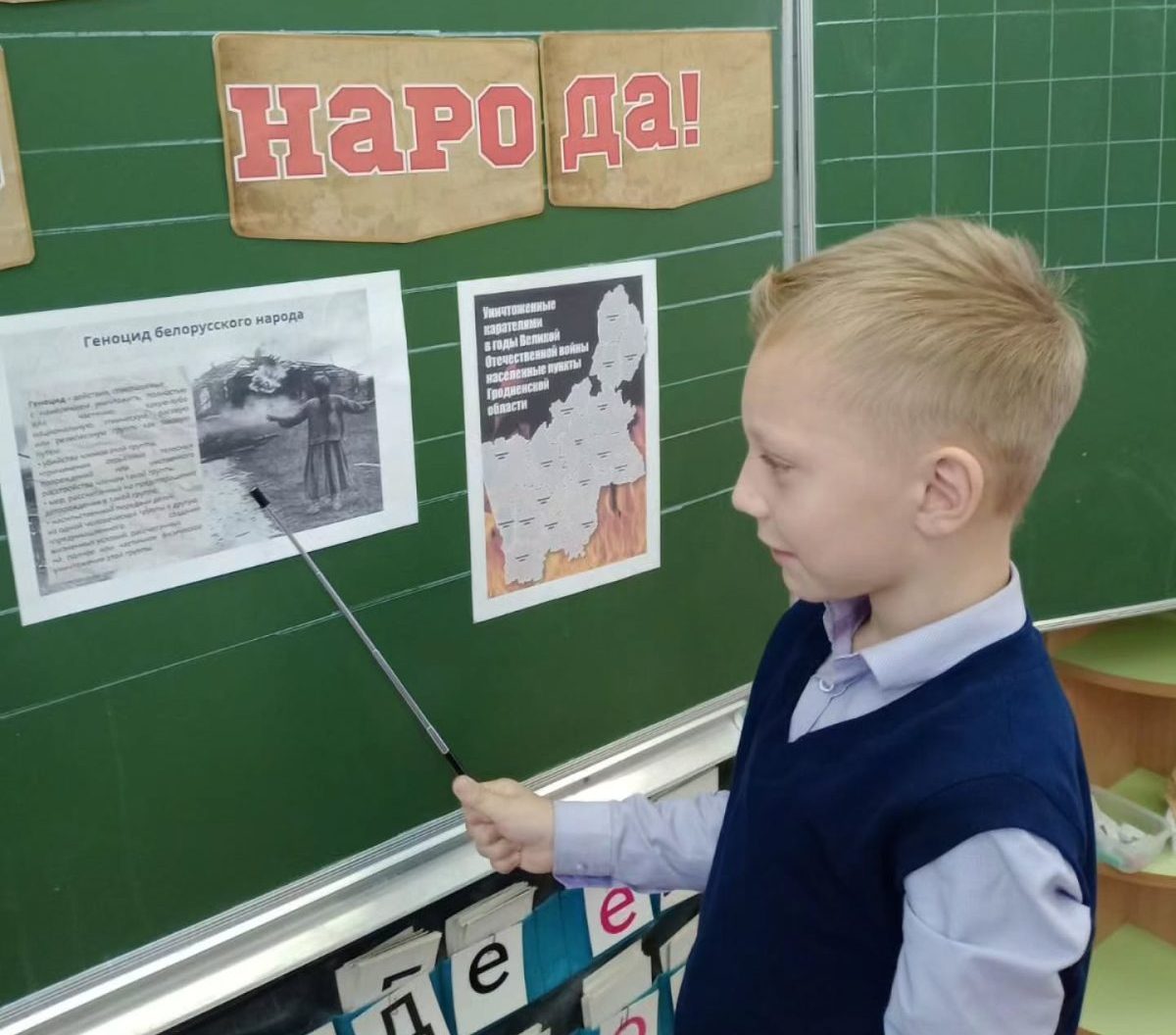 Школьник стоит у доски и указывает указкой на геноцид беларуского народа
